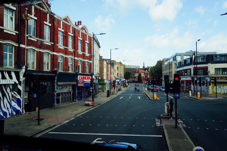 A wide view of a city street at daybreak showing a row of historic multi-storey buildings with detailed architectural facades, some with ornate decorations and bay windows, lining the left side of the